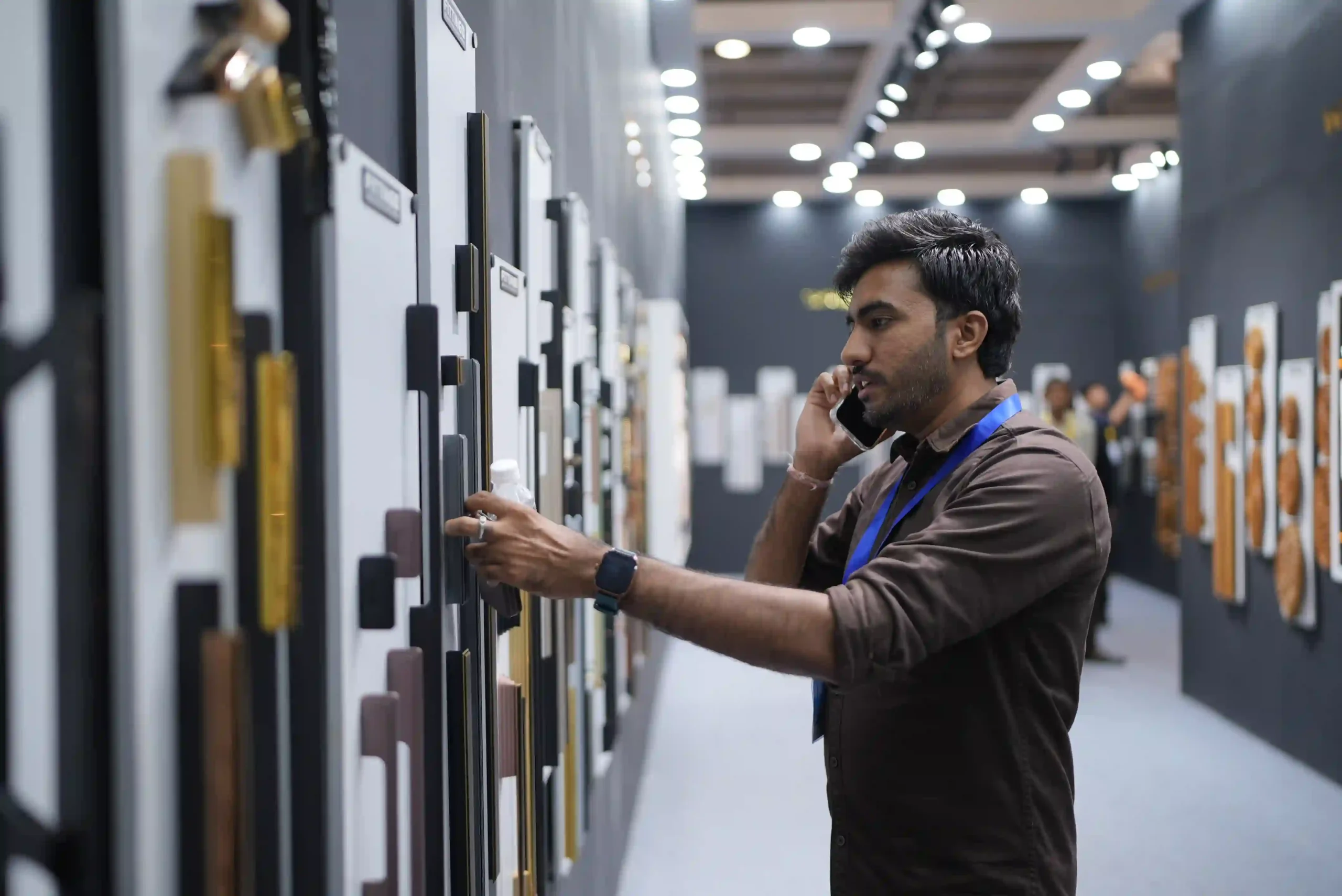 A visitor on the phone reaching for a handle sample on the display wall