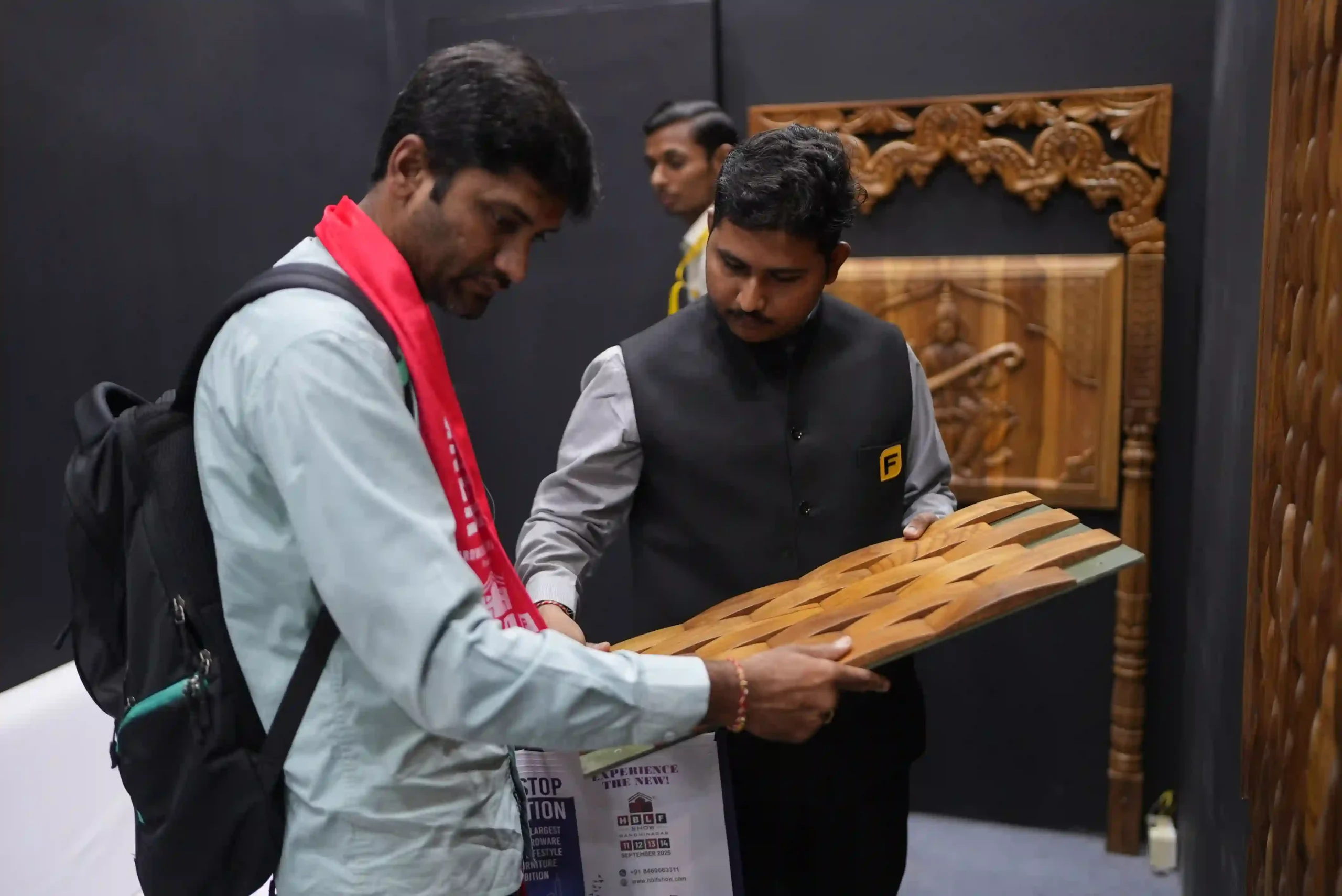 A Fittingo team member showing a woven timber panel sample to a visitor