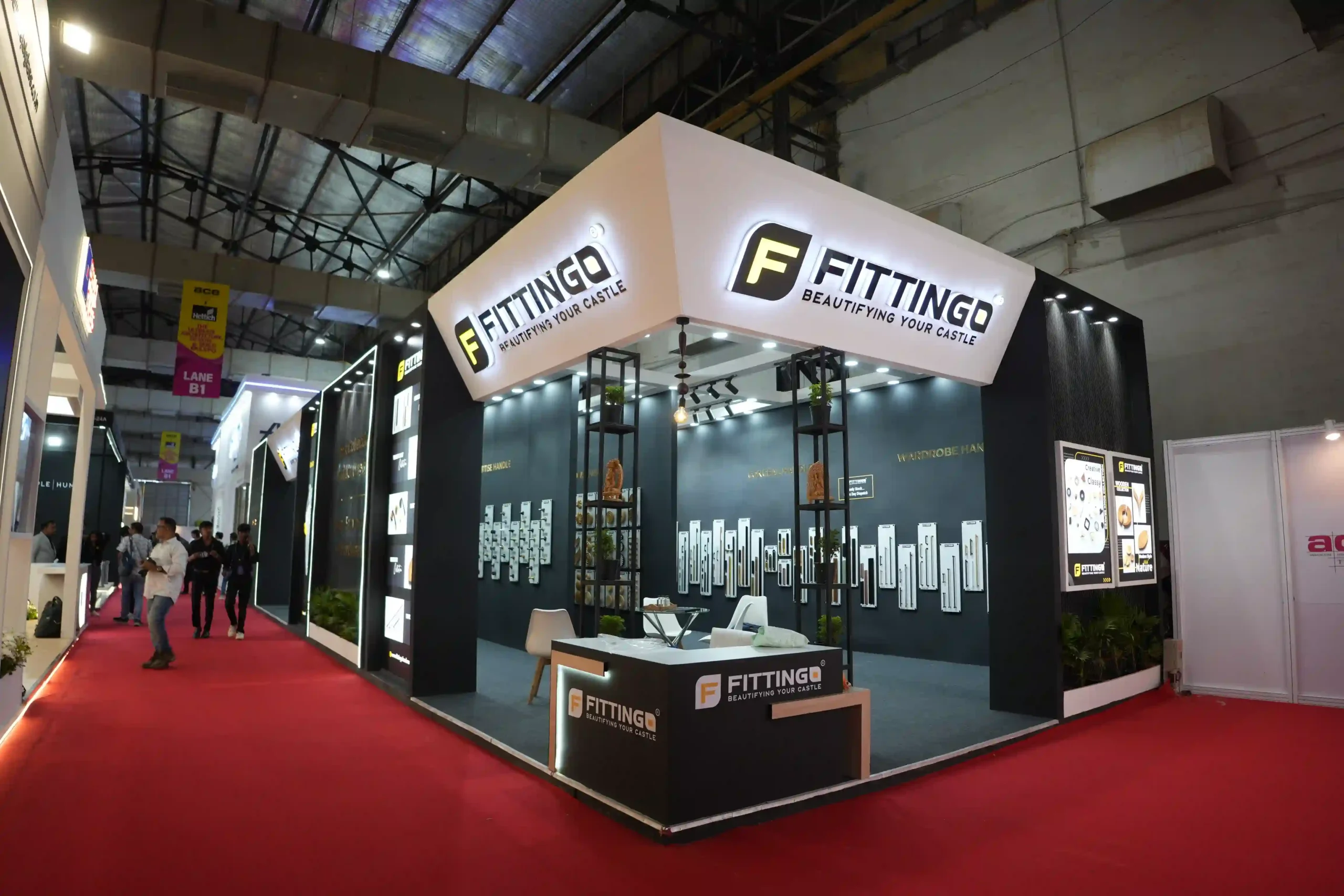 Corner view of the Fittingo stand from the aisle, showing the canopy and branded reception desk