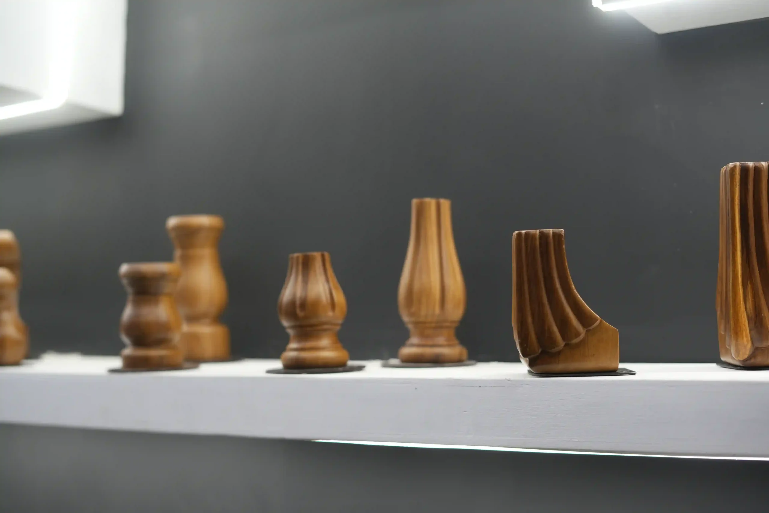 row of turned wooden furniture legs on an illuminated white display shelf