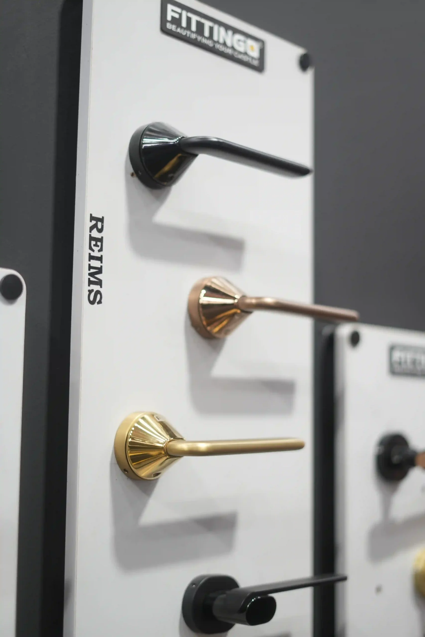 Close-up of three fluted lever handles in polished gold, rose gold and black
