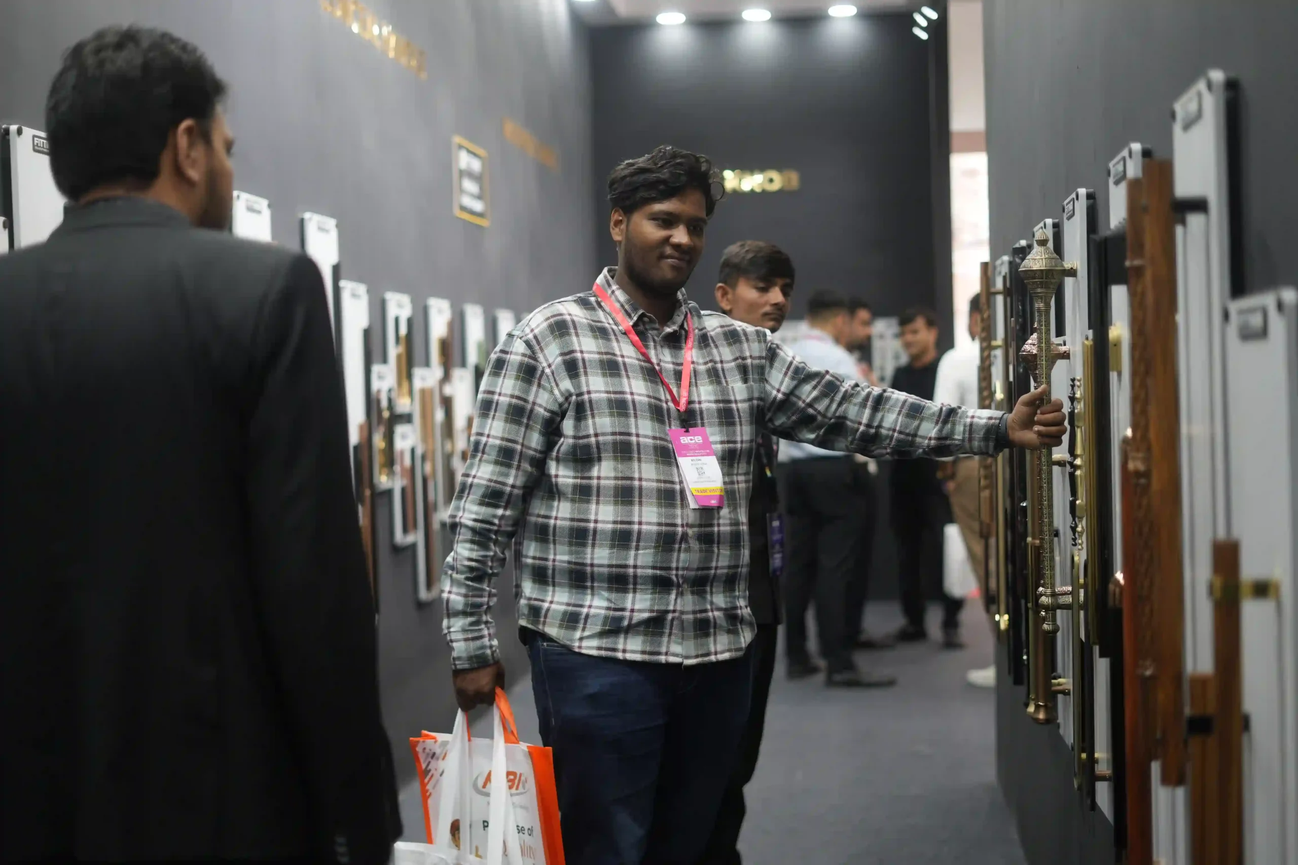 A trade visitor reaching for an ornate brass main-door pull on the display wall