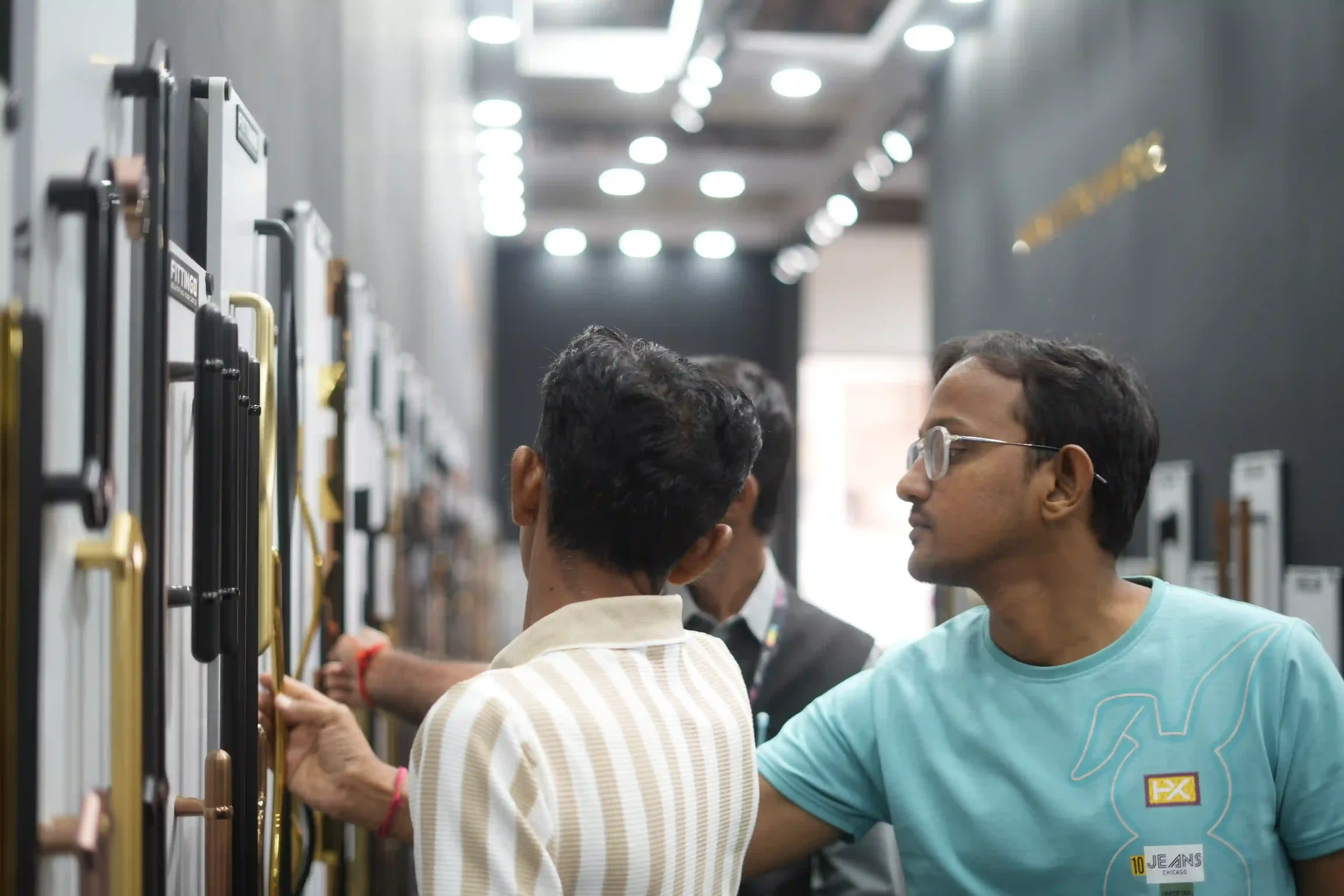 Two visitors examining brass and black handle profiles on the sample boards