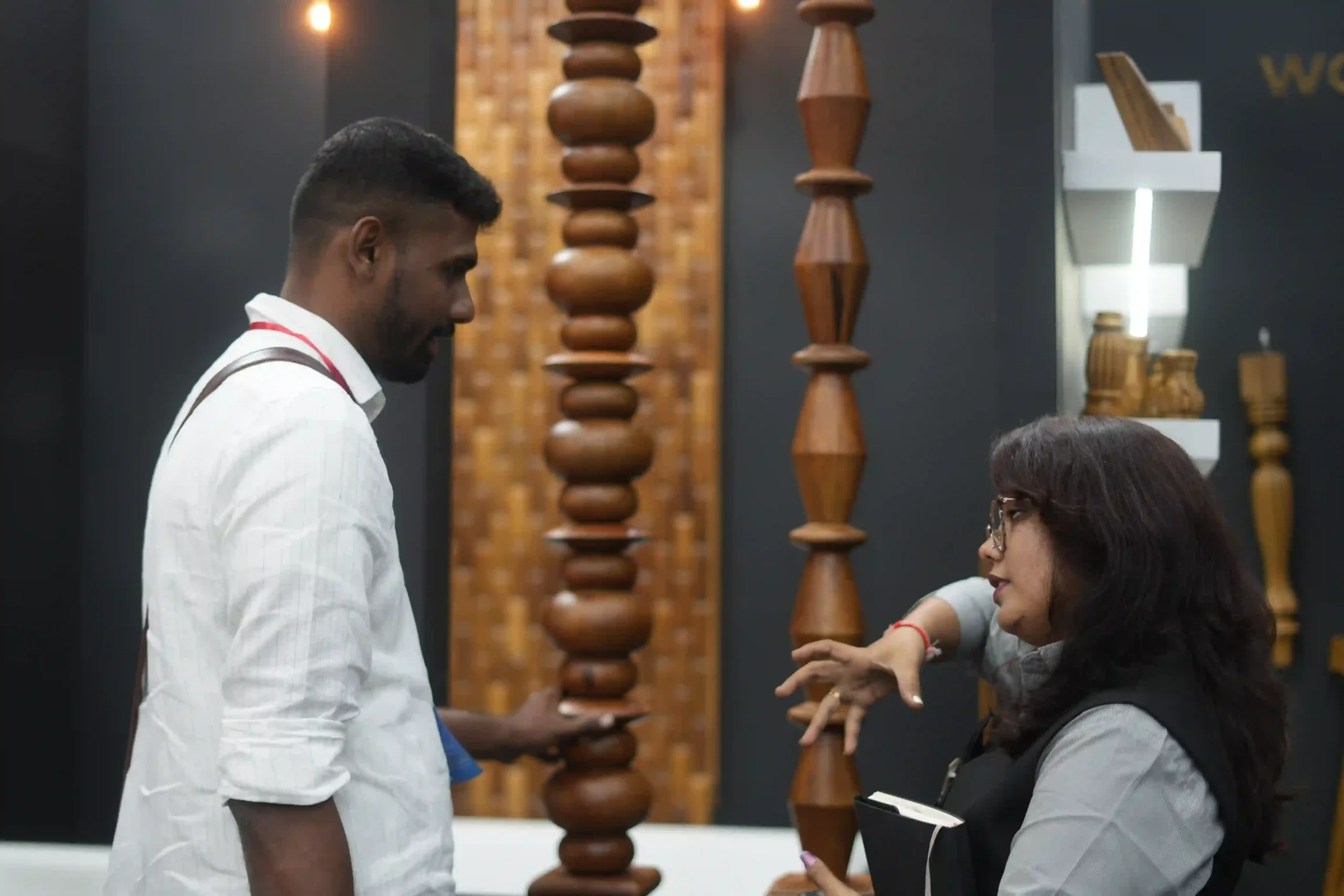 Two visitors in conversation in front of the turned wooden column display