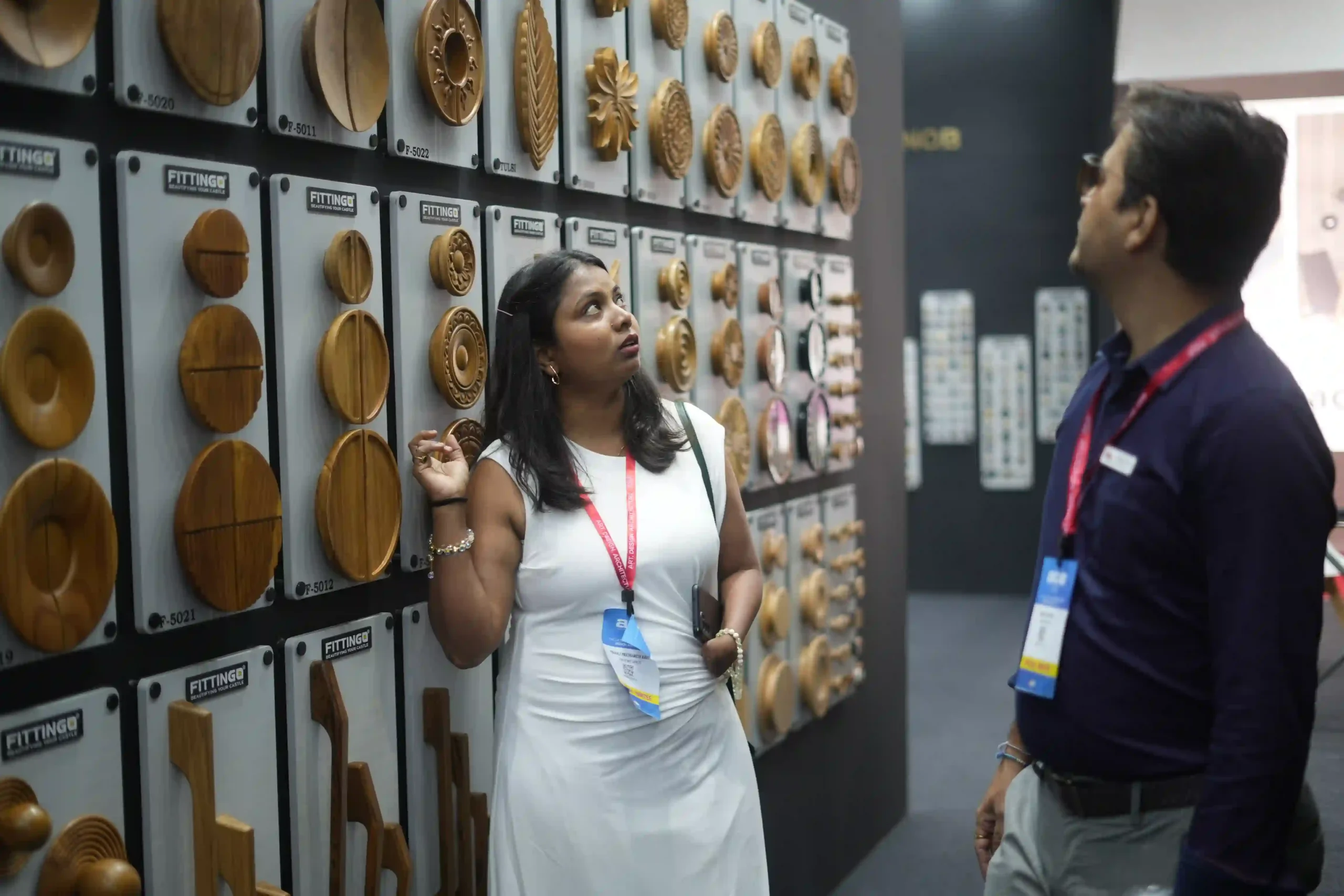 A visitor studying the wall of carved wooden rosettes on numbered Fittingo plaques